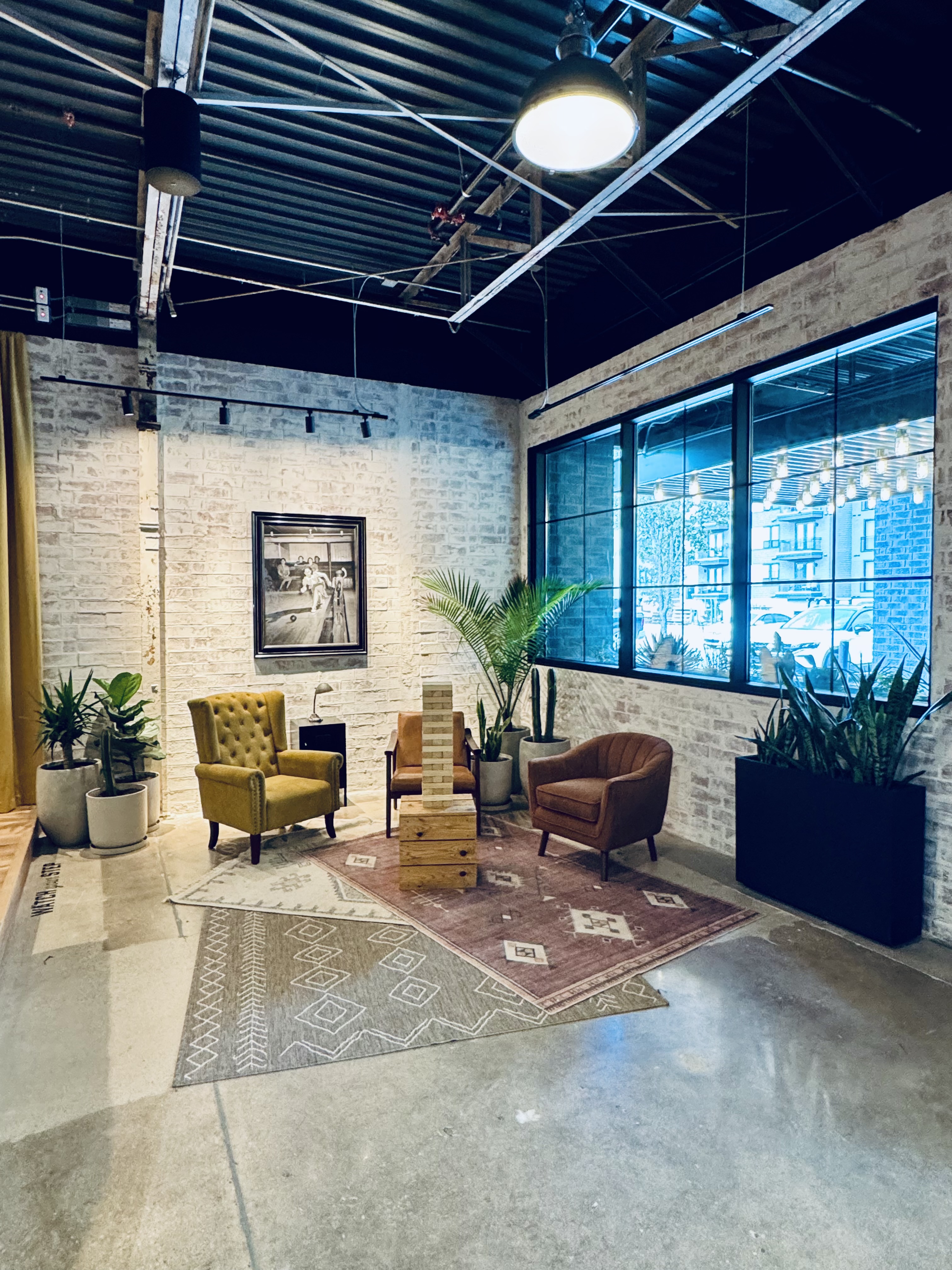 Interior lounge corner with potted palms, snake plants and cactus against whitewashed brick